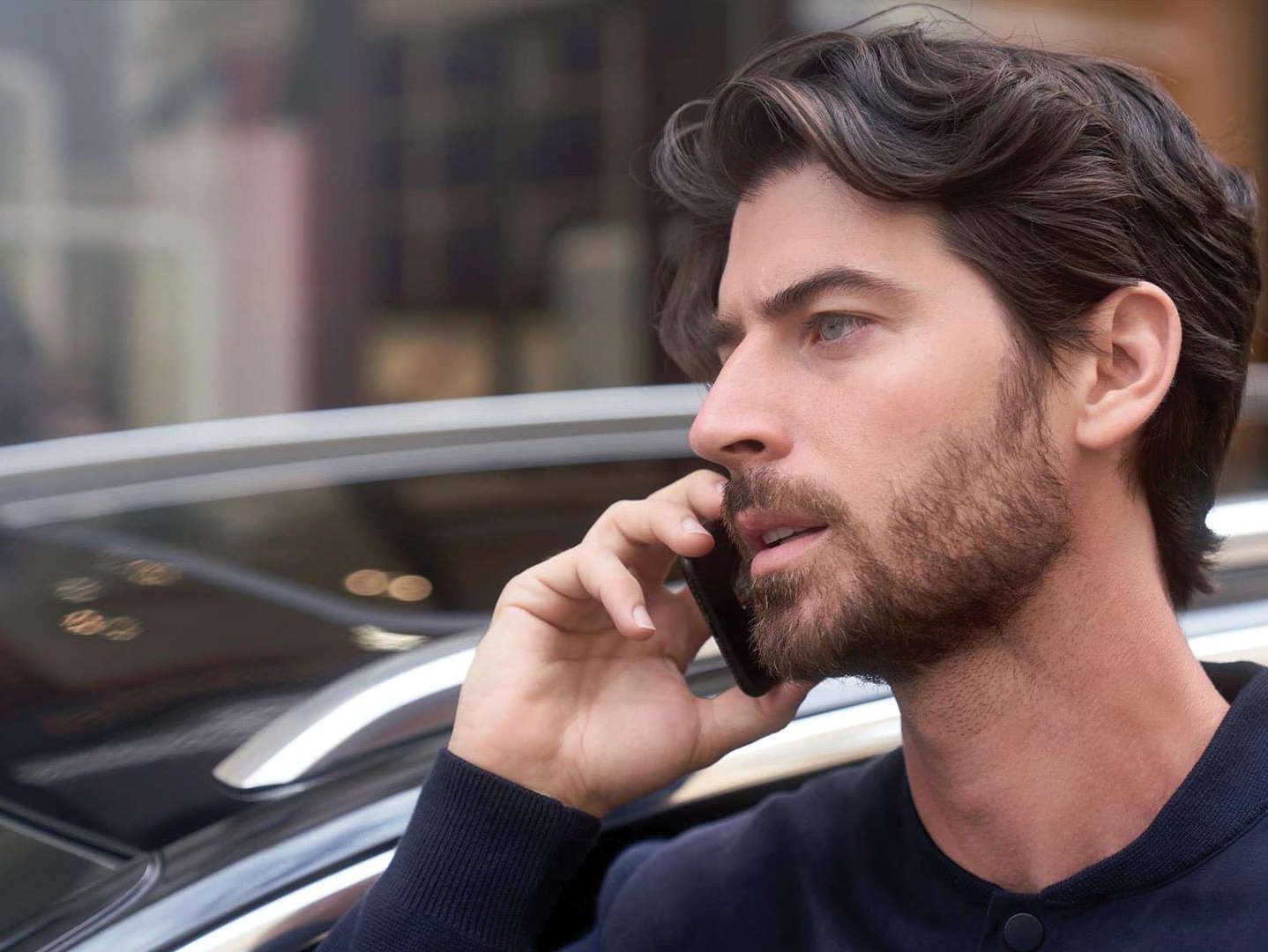 Чоловік тримає телефон біля вуха, стоячи перед автомобілем Peugeot