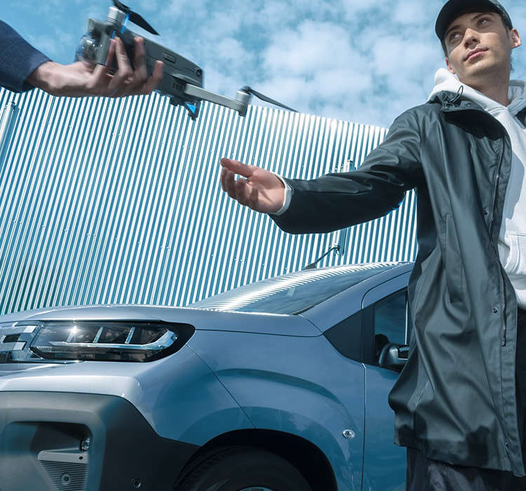 Peugeot Partner, вигляд спереду з лівого боку, два чоловіки з коптером